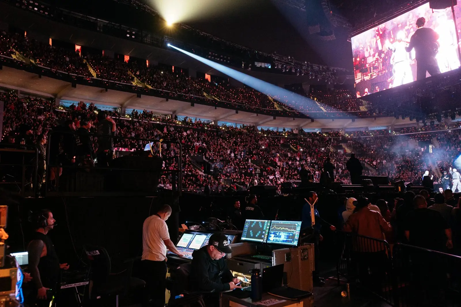 Front of house at the Intuit Dome during Fuerza Regida: engineers at the console, a sold-out crowd and the IMAG screen behind them.