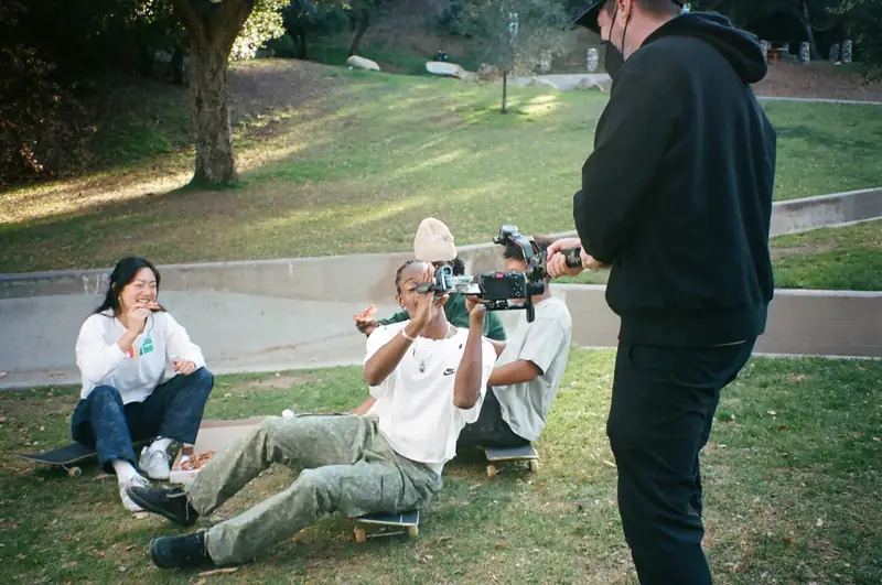 An operator shooting handheld while talent sits on skateboards during a Nike shoot.